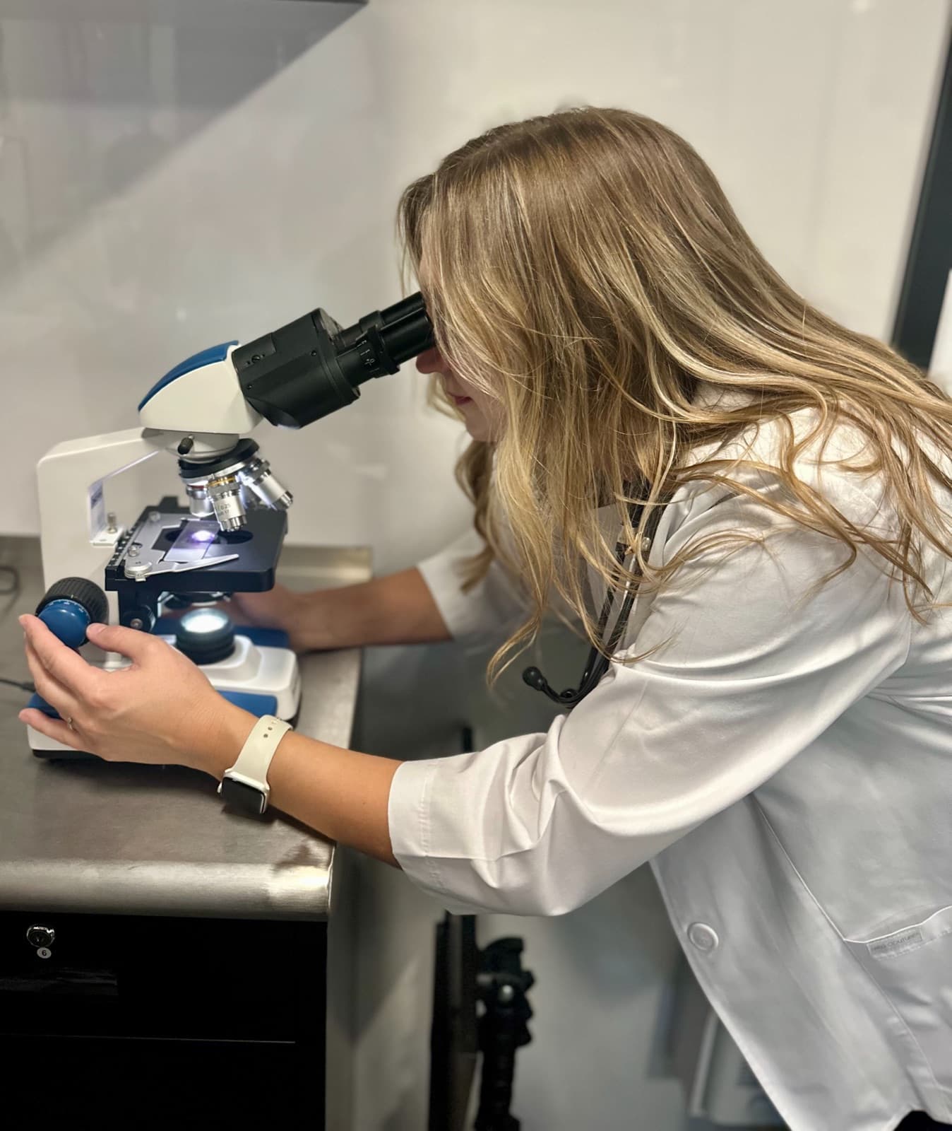 Dr. Mackenzie Deviney running in-home lab work under a microscope in the Blessed Paws mobile unit
